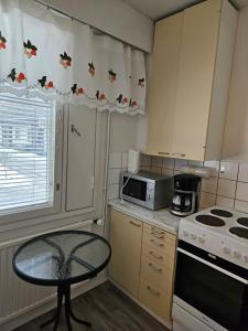 a small kitchen with a table and a microwave at Rivitaloyksiö Vilppulassa in Vilppula