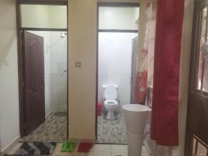 a bathroom with a toilet and a sink and a door at Kismet Hideaway in Nairobi