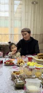 a woman and a child sitting at a table with food at Baburs guest house in Orgochor +15 photos