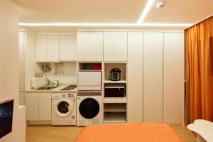 a kitchen with white cabinets and a washer and dryer at 스태이링크 Staylink in Seoul