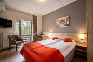 a hotel room with a large bed with an orange blanket at Hotel Bergrust in Bemelen