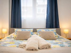 a bed with two pillows and a blanket on it at Appartement Centre Saint-Omer, Parking privé gratuit in Saint-Omer