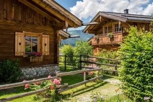 a log house with a fence and flowers in front of it at almlust - hotel, apartments, chalets in Flachau