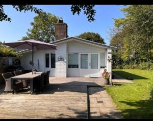 a house with a table and an umbrella in front of it at Villa Rosa in Andijk