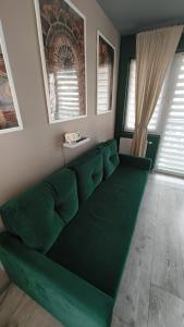 a green couch in a living room with windows at YoniHarmony - 2 parking places in Sosnowiec
