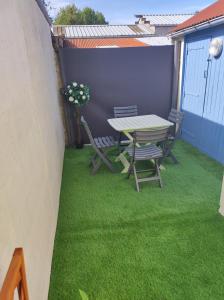 a table and chairs on a patio with green grass at L Atelier de papa in Dargnies