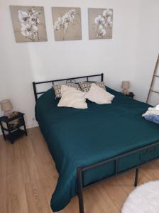 a bedroom with a green bed with pillows on it at L Atelier de papa in Dargnies