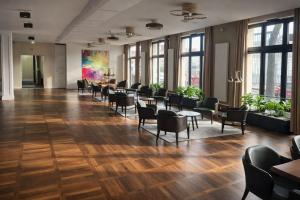 a waiting room with chairs and tables and windows at SOLWO Suites Berlin Charlottenburg in Berlin