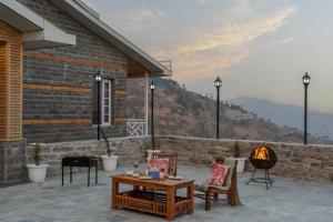 a patio with a table and chairs and a fireplace at SaffronStays Alpine Blue, Theog - 6BR Villa with Valley Views in Shimla +57 photos