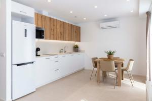 a white kitchen with a table and a refrigerator at Apartamentos Armonia Peñíscola in Peniscola