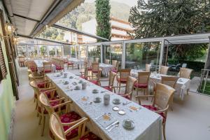 a restaurant with white tables and chairs and windows at Albergo al Cervo - Gasthof zum Hirschen in Lagundo