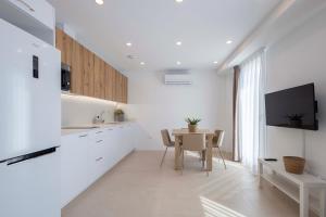 a kitchen with white cabinets and a table with chairs at Apartamentos Armonia Peñíscola in Peniscola +27 photos