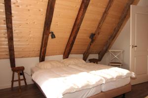 a bed in a room with wooden ceilings at Scholtenhoes in Hezingen