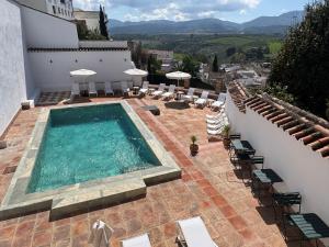 a swimming pool on top of a building with chairs at Avanel Boutique Apartments in Ronda