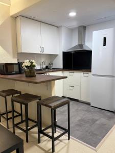 a kitchen with white cabinets and a counter and stools at Hotel lázaro in Calamocha
