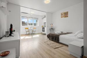 a white bedroom with a bed and a table with chairs at FLH - Cozy Heaven in Chiajna +15 photos