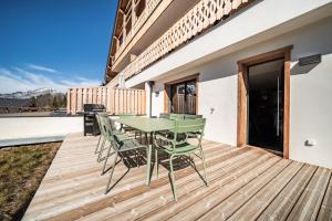 a wooden deck with a green table and chairs on it at Apartment Clano, Châtel - by EMERALD STAY in Châtel