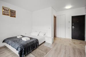 a white bedroom with a bed and a wooden floor at FLH - Cozy Heaven in Chiajna