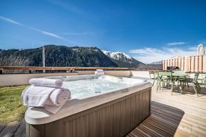 a jacuzzi tub on a balcony with a table and chairs at Apartment Clano, Châtel - by EMERALD STAY in Châtel