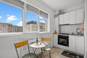 a kitchen with a table and two chairs and two windows at FLH - Cozy Heaven in Chiajna