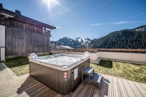 a hot tub on a deck with mountains in the background at Apartment Clano, Châtel - by EMERALD STAY in Châtel +34 photos