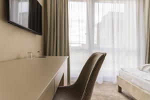 ein Schlafzimmer mit einem Schreibtisch und einem Stuhl vor einem Fenster in der Unterkunft Hotel Atlantis Wellness & Conference in Hajdúszoboszló