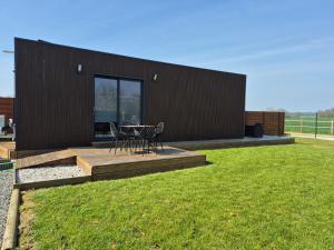 ein schwarzes Haus mit einem Tisch und Stühlen auf einer Terrasse in der Unterkunft NATIBOXflo in Saint-Michel-de-Chavaignes