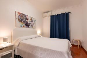 a bedroom with a white bed and a blue curtain at Casa do Lado, Flores Açores in Lajes das Flores
