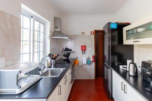 a kitchen with a sink and a refrigerator at Casa do Lado, Flores Açores in Lajes das Flores