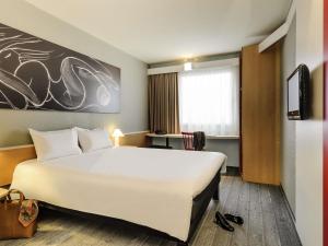 a hotel room with a large white bed and a window at ibis Hotel Hannover City in Hannover