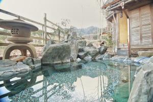 a pool of water in front of a house at 24時間源泉かけ流しを ひとりじめできる 一棟貸しVilla安曇野 in Azumino