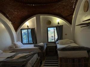 a room with three beds and two windows at Turia Hotel in Aswan