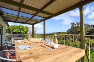 a wooden table with a bottle of wine on a deck at The Salt Shack in Mallacoota