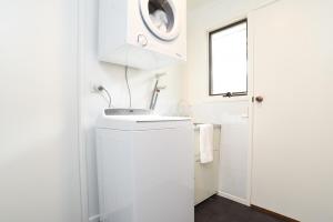a white bathroom with a sink and a washing machine at The Salt Shack in Mallacoota +14 photos