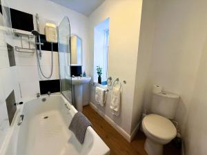 a bathroom with a tub and a toilet and a sink at Ardmore House in Ventnor +14 photos