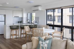 a kitchen and living room with a table and chairs at Summer Cove on the Ocean with Pool in Coolum Beach