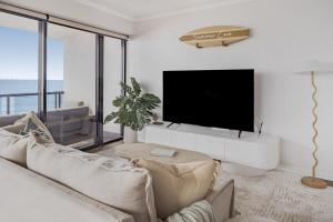 a living room with a couch and a flat screen tv at Summer Cove on the Ocean with Pool in Coolum Beach