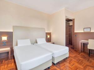 a bedroom with a white bed and a desk at B&B HOTEL Habitat Giussano in Giussano