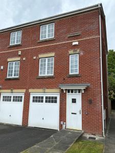a red brick building with two white garage doors at Mmc serviced accommodation 2 in Leigh