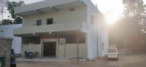 a white building with a car parked in front of it at Pie Restuarant and HomeStay in Baihar
