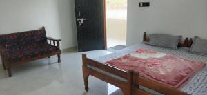 a bedroom with a bed and a chair and a door at Pie Restuarant and HomeStay in Baihar +2 photos
