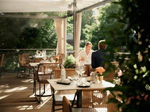 a man and woman sitting at a table on a patio at Hotel Krone ****S in Tübingen