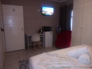 a bedroom with a bed and a table and a microwave at B&P Guesthouse in Boksburg