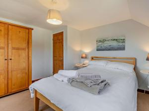 a bedroom with a white bed and a wooden cabinet at 3 Bed in Bude oc-trvvv in Poughill