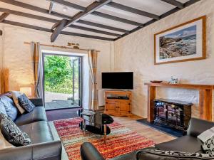 a living room with a couch and a fireplace at 3 Bed in Bude oc-stafa in Poughill