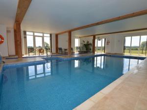 a large swimming pool with blue water in a building at 2 Bed in Sherborne oc-folki in Long Burton