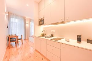 a kitchen with white cabinets and a wooden floor at FindMe InPorto Bonfim in Porto