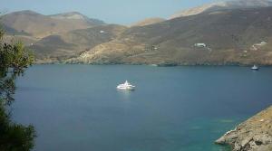 a boat in a large body of water with mountains at Asvestoti ciel fish house in Astypalaia