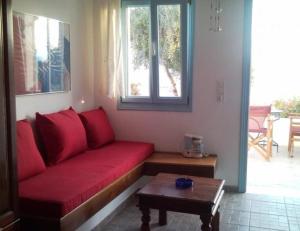 a red couch in a living room with a table at Asvestoti ciel fish house in Astypalaia