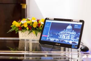 a laptop computer sitting on a glass table with a vase of flowers at LaHouse Rome by Premium Suites Collection in Rome +29 photos